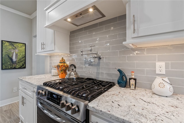 kitchen featuring tasteful backsplash, light stone counters, white cabinets, and stainless steel range with gas stovetop