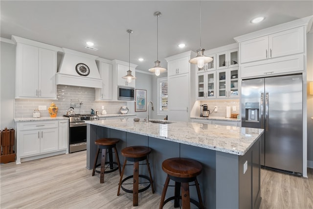 kitchen with sink, appliances with stainless steel finishes, decorative light fixtures, white cabinets, and custom exhaust hood