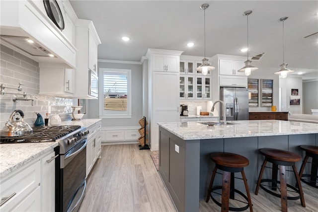 kitchen featuring white cabinets, appliances with stainless steel finishes, decorative backsplash, and hanging light fixtures