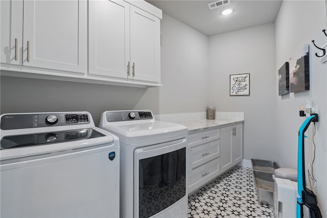 laundry room featuring washer and clothes dryer and cabinets