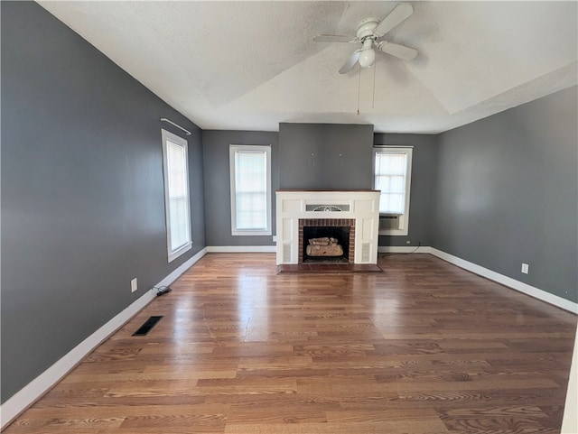 unfurnished living room featuring hardwood / wood-style flooring, a brick fireplace, ceiling fan, and lofted ceiling