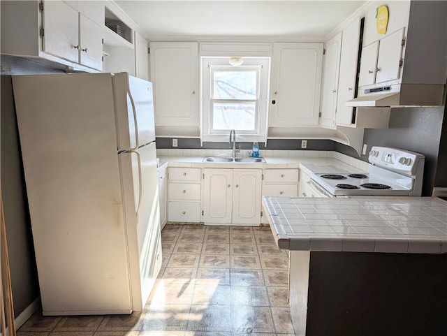 kitchen featuring white appliances, white cabinets, sink, light tile patterned floors, and tile counters