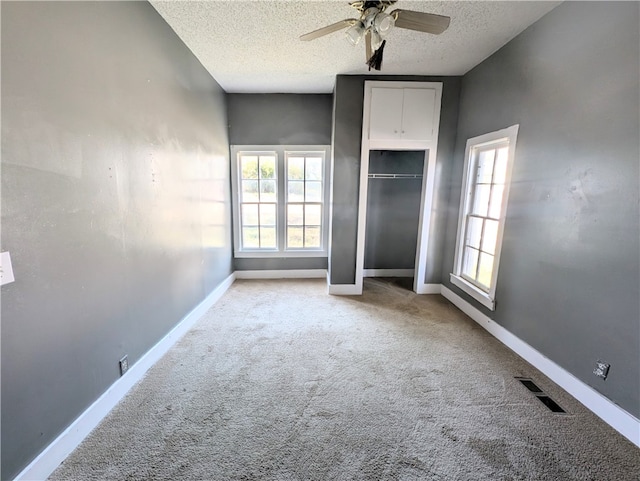 unfurnished bedroom with ceiling fan, a closet, light colored carpet, and a textured ceiling