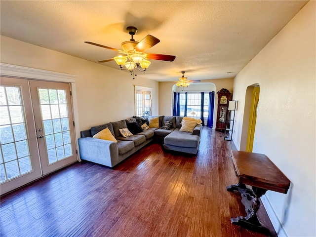 living room with ceiling fan, a healthy amount of sunlight, dark wood-type flooring, and french doors