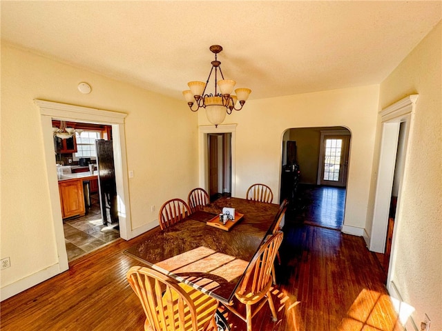 dining room featuring a healthy amount of sunlight, dark hardwood / wood-style floors, and a notable chandelier