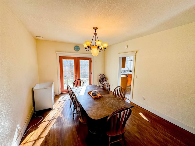 dining room with a textured ceiling, french doors, a notable chandelier, and hardwood / wood-style flooring