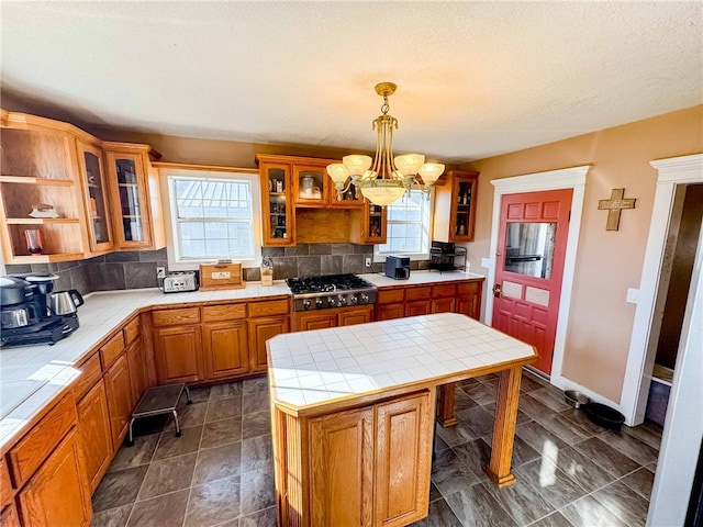 kitchen featuring tile counters, a center island, hanging light fixtures, and a wealth of natural light