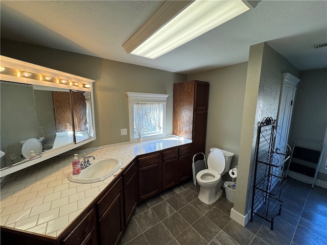 bathroom featuring vanity, toilet, and a textured ceiling