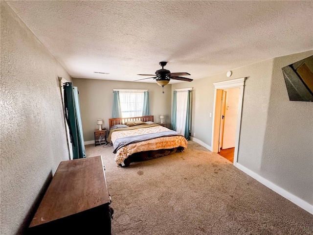 bedroom with ceiling fan, light carpet, and a textured ceiling