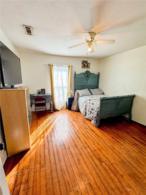 bedroom featuring ceiling fan, wood-type flooring, and a textured ceiling