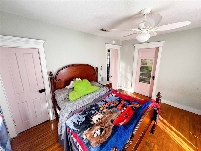 bedroom featuring ceiling fan, dark hardwood / wood-style flooring, and a textured ceiling