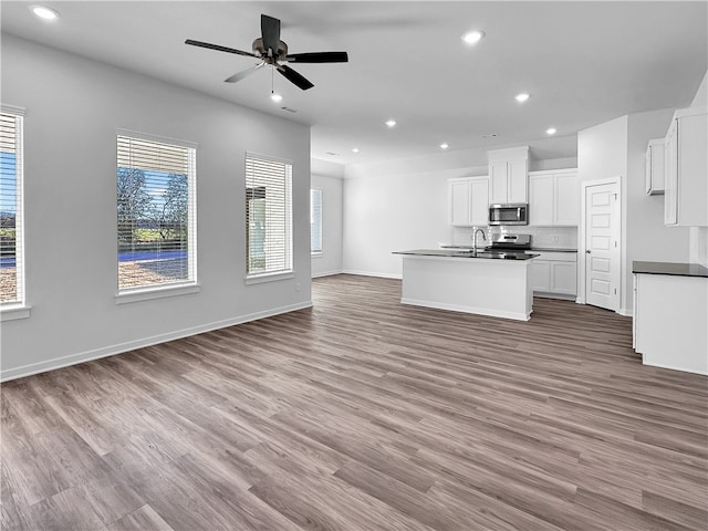 kitchen featuring a center island with sink, white cabinets, stainless steel appliances, and light hardwood / wood-style flooring