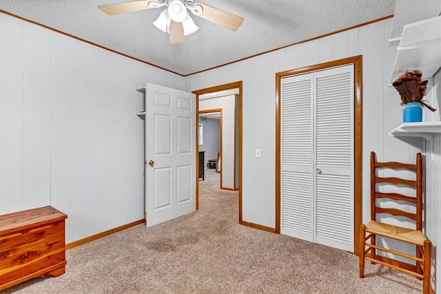 carpeted bedroom with a textured ceiling, a closet, ceiling fan, and crown molding