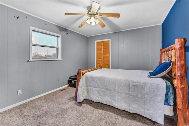 bedroom featuring carpet flooring, ceiling fan, wooden walls, and a closet