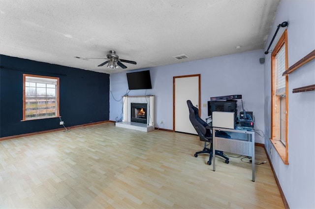 home office with ceiling fan, light wood-type flooring, and a textured ceiling