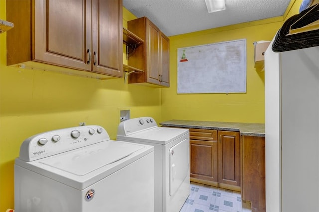 washroom featuring cabinets, washing machine and dryer, and a textured ceiling