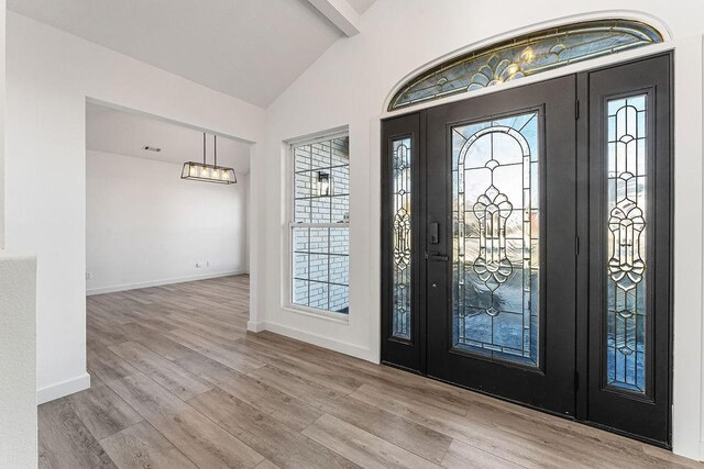 foyer featuring light wood-type flooring and lofted ceiling with beams