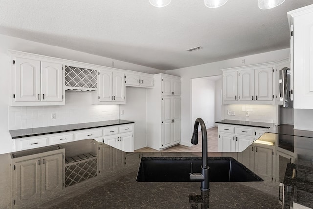 kitchen featuring backsplash, white cabinetry, sink, and wood-type flooring