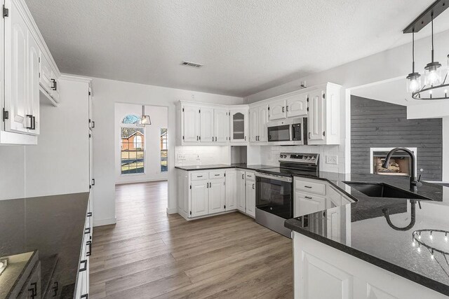 kitchen with hanging light fixtures, sink, white cabinets, and stainless steel appliances