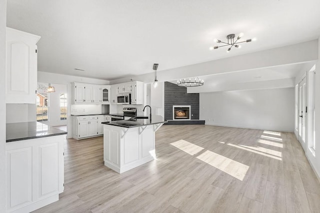 kitchen with white cabinetry, light wood-type flooring, a kitchen breakfast bar, a notable chandelier, and stainless steel appliances