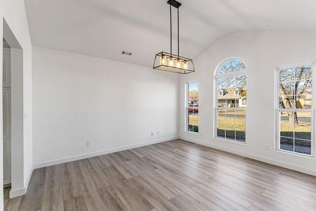 unfurnished dining area with light hardwood / wood-style floors and vaulted ceiling