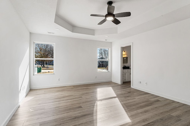 unfurnished room with ceiling fan, a raised ceiling, and light hardwood / wood-style flooring