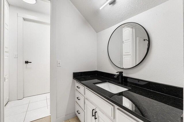 bathroom featuring a textured ceiling, vanity, tile patterned floors, and lofted ceiling