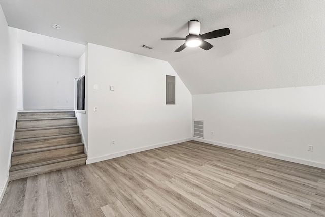 additional living space featuring a textured ceiling, light wood-type flooring, ceiling fan, and lofted ceiling