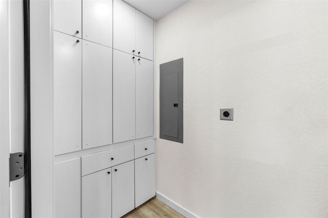 clothes washing area featuring light hardwood / wood-style floors, electric panel, cabinets, and hookup for an electric dryer