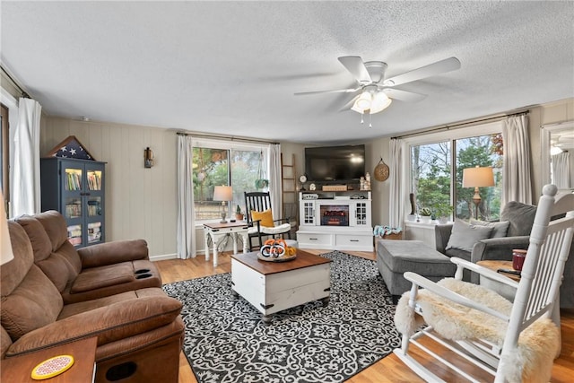 living room with hardwood / wood-style flooring, ceiling fan, and a textured ceiling