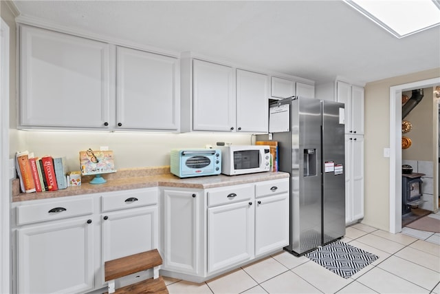 kitchen featuring white cabinets, stainless steel fridge, and light tile patterned floors