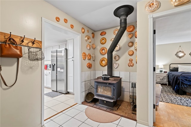 interior space featuring tile patterned floors, a wood stove, and tile walls