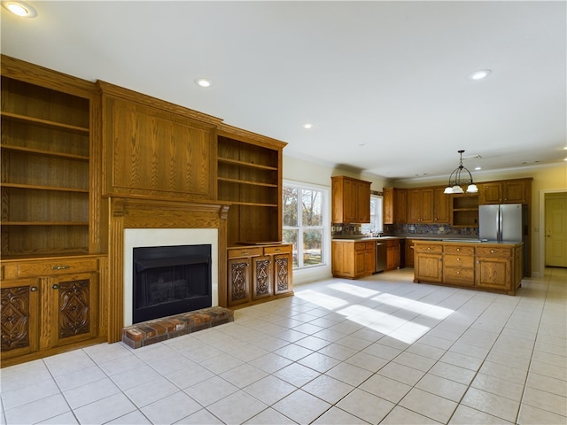 kitchen featuring pendant lighting, crown molding, light tile patterned floors, a fireplace, and stainless steel appliances