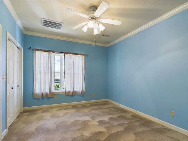 carpeted empty room with ceiling fan and crown molding