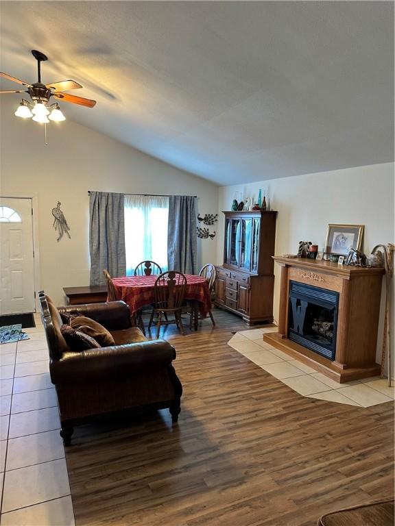 living room featuring light wood-type flooring, ceiling fan, and vaulted ceiling