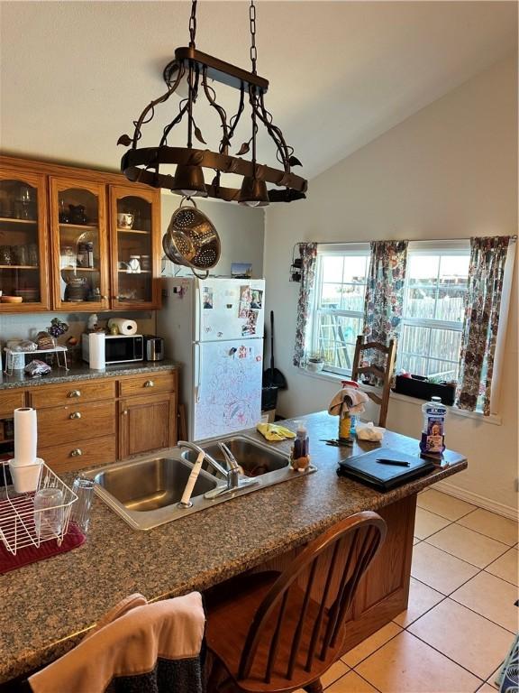 kitchen featuring lofted ceiling, white refrigerator, light tile patterned flooring, and sink