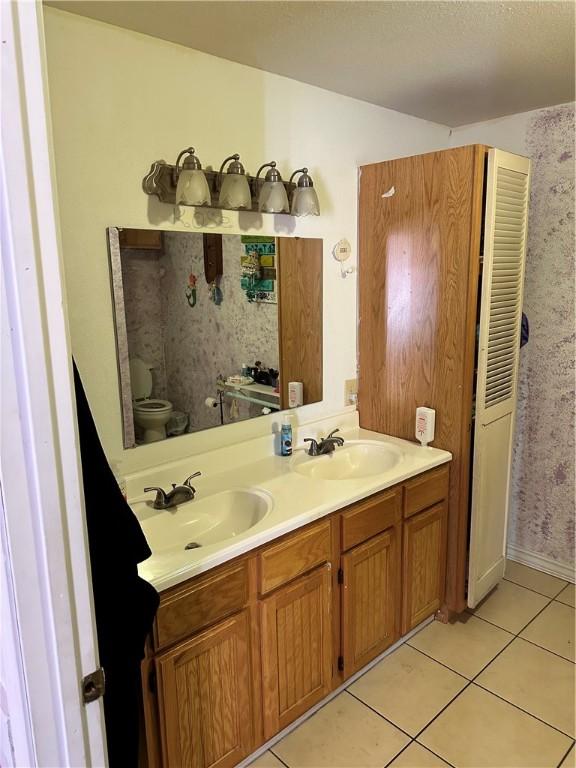 bathroom featuring toilet, tile patterned flooring, and vanity