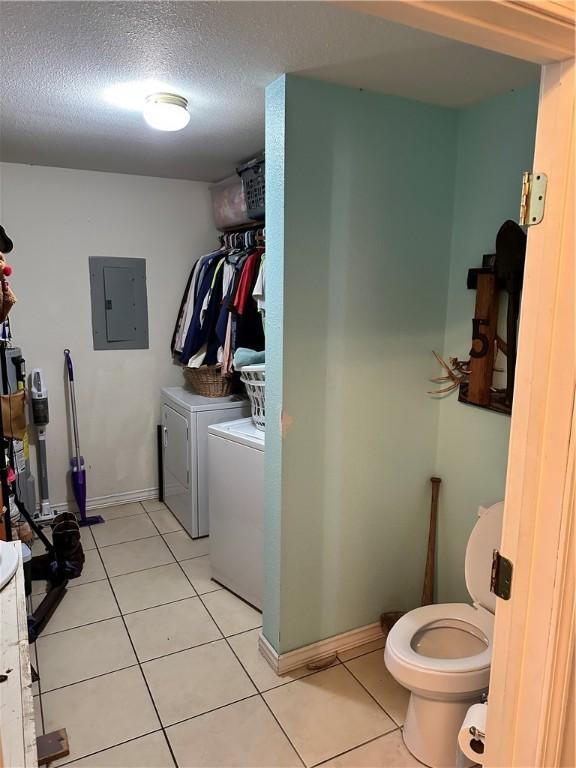 laundry area with washer and clothes dryer, a textured ceiling, light tile patterned flooring, and electric panel