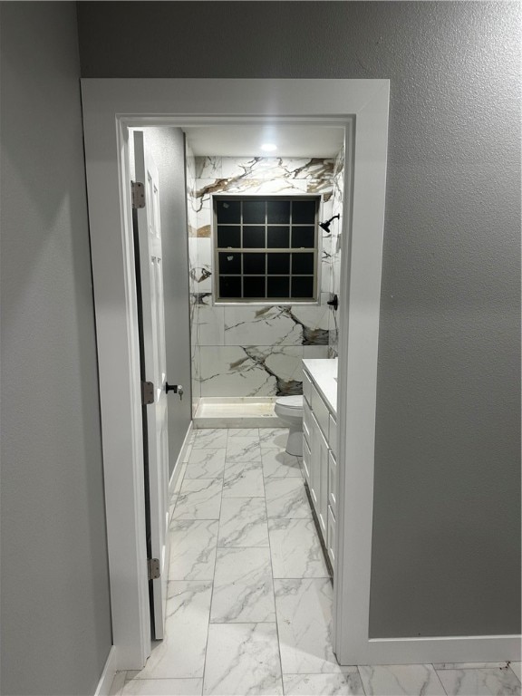 bathroom featuring a shower, vanity, and toilet