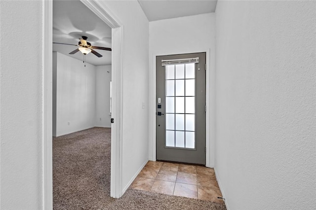 doorway featuring light colored carpet and ceiling fan