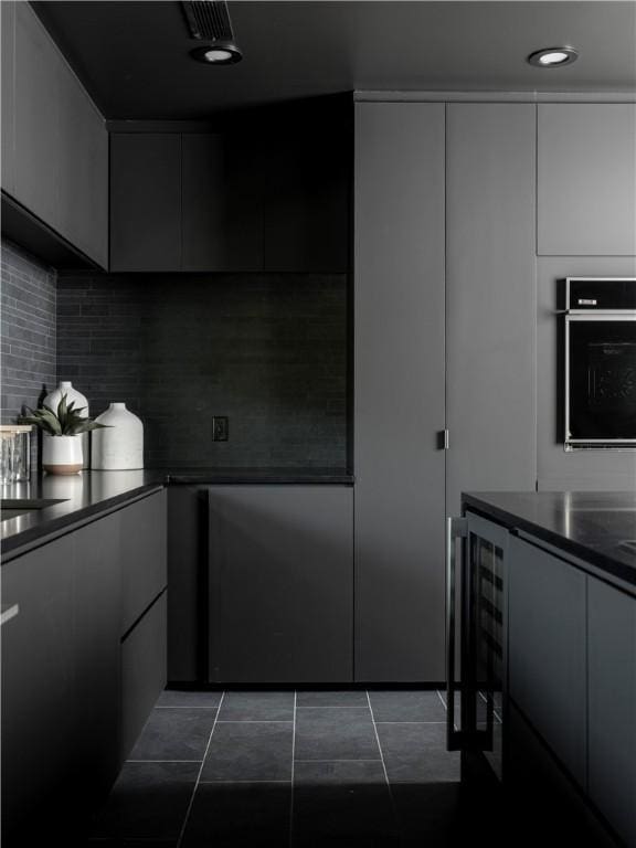 kitchen with white cabinets, oven, beverage cooler, and dark tile patterned flooring