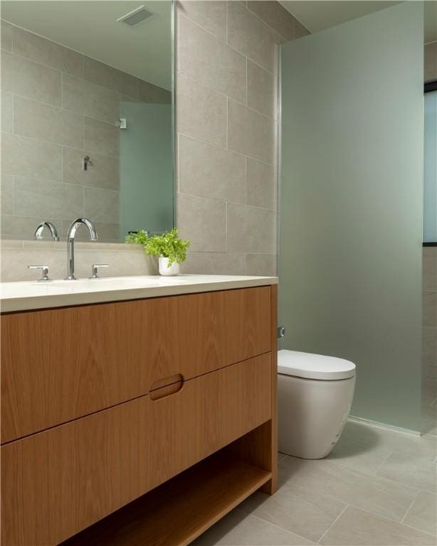 bathroom with vanity, toilet, tile patterned flooring, and tile walls