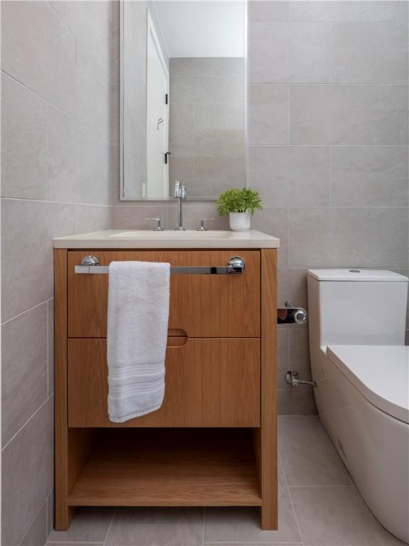 bathroom featuring tile walls, vanity, tile patterned floors, and toilet