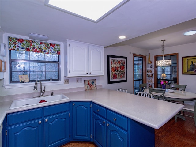 kitchen with blue cabinetry, decorative light fixtures, kitchen peninsula, and sink