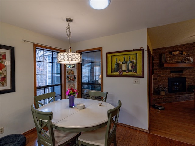 dining area with dark hardwood / wood-style floors and a brick fireplace