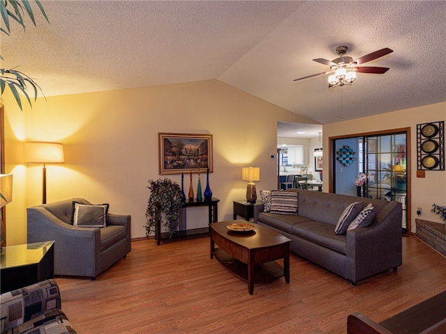 living room with wood-type flooring, a textured ceiling, ceiling fan, and lofted ceiling