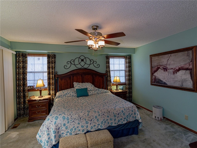 bedroom featuring a textured ceiling, light colored carpet, and ceiling fan