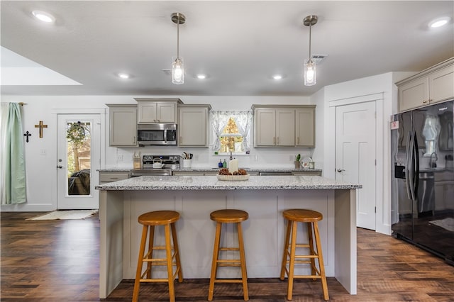 kitchen featuring a kitchen breakfast bar, hanging light fixtures, a kitchen island, dark hardwood / wood-style flooring, and stainless steel appliances