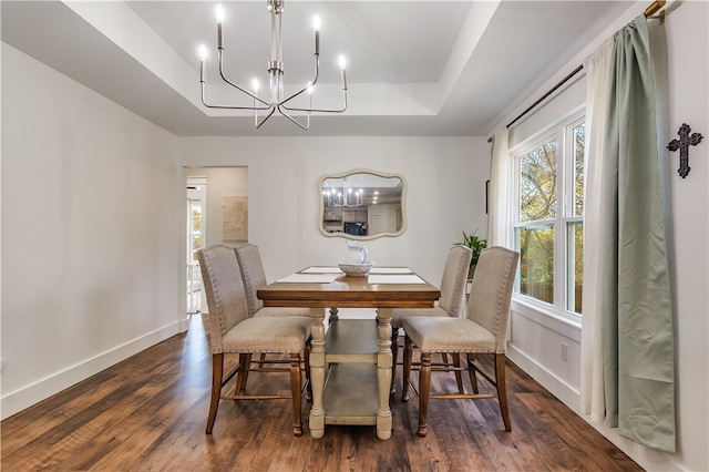 dining room with a raised ceiling, dark hardwood / wood-style floors, and a notable chandelier