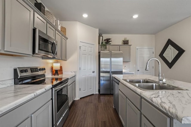 kitchen with dark hardwood / wood-style flooring, light stone counters, stainless steel appliances, sink, and gray cabinets